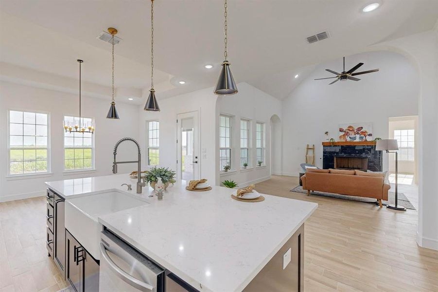 Kitchen with decorative light fixtures, stainless steel dishwasher, a fireplace, and an island with sink