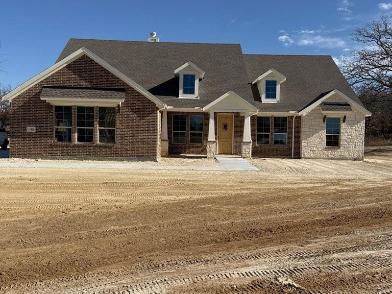 View of front of house featuring roof with shingles, brick siding, and stone siding