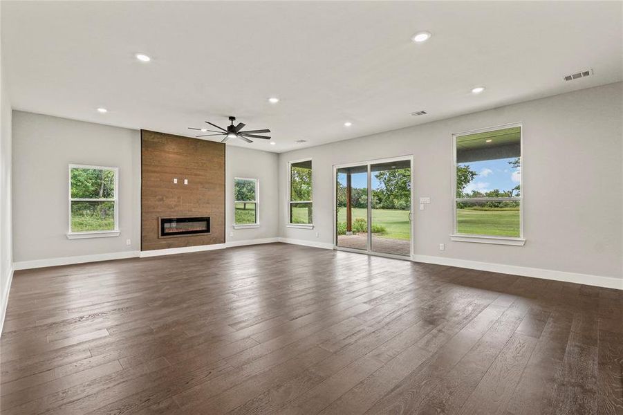 Living room featuring a ceiling fan, recessed lighting, healthy amount of natural light, dark wood-style flooring, and a fireplace
