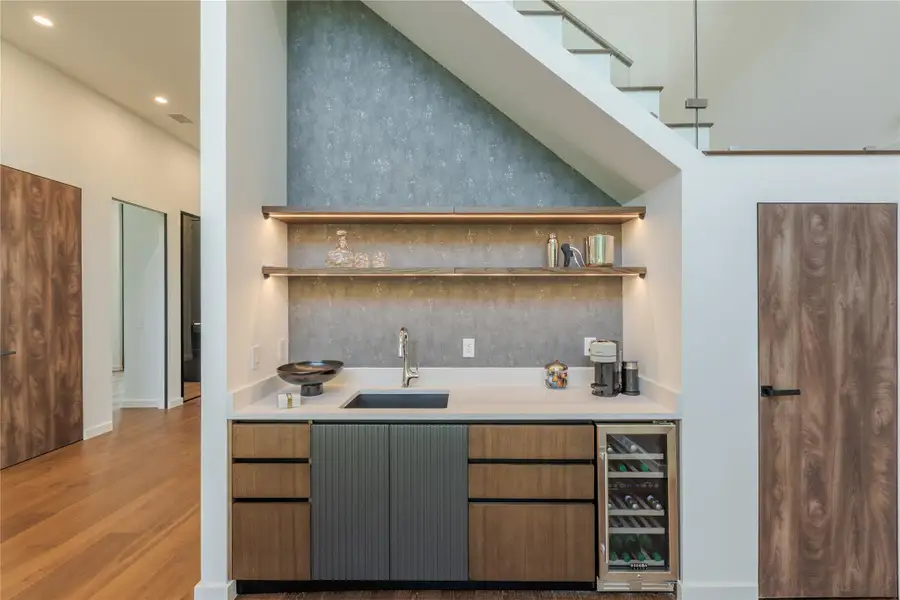 A refined wet bar, neatly integrated under a sleek staircase, offers sophisticated entertaining.