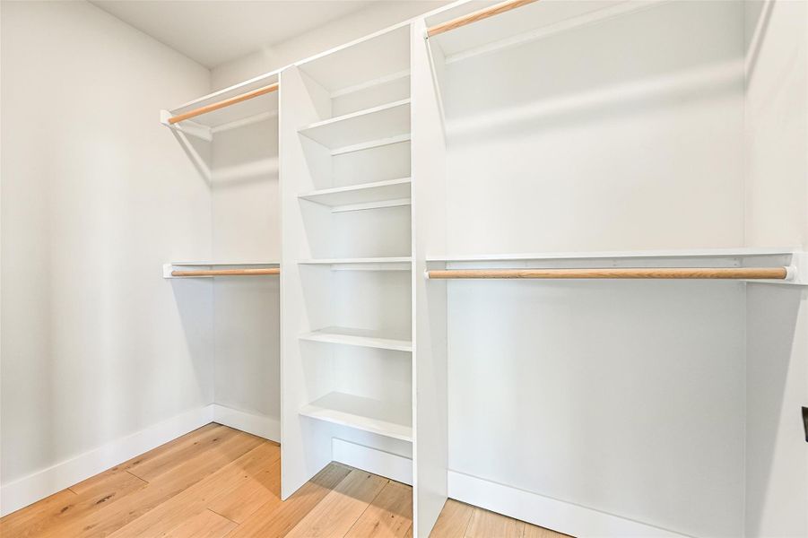 Custom built-ins with sleek open shelving and dual hanging rods provide ample room for wardrobe organization.
