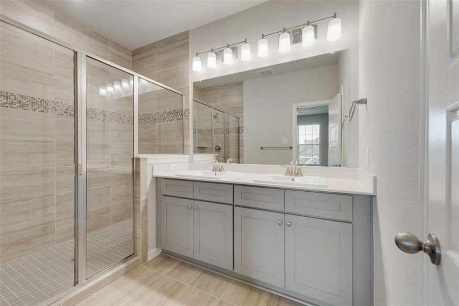 Bathroom with tile patterned flooring, dual vanity, and a shower with door