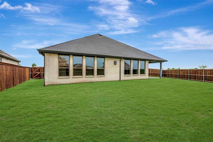 Expansive backyard featuring a lush lawn, privacy fencing, and a covered patio