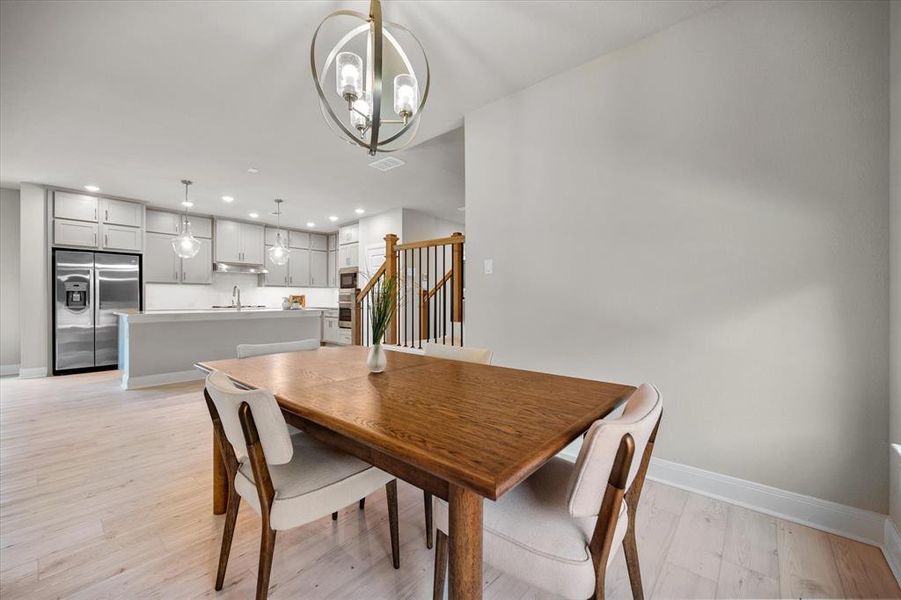 Dining room featuring a chandelier, recessed lighting, light wood-type flooring, and stairs Dining room featuring a chandelier, recessed lighting, light wood-type flooring, and stairs