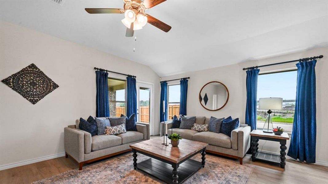 Living area with light wood-type flooring, healthy amount of natural light, a ceiling fan, and vaulted ceiling Living area with light wood-type flooring, healthy amount of natural light, a ceiling fan, and vaulted ceiling