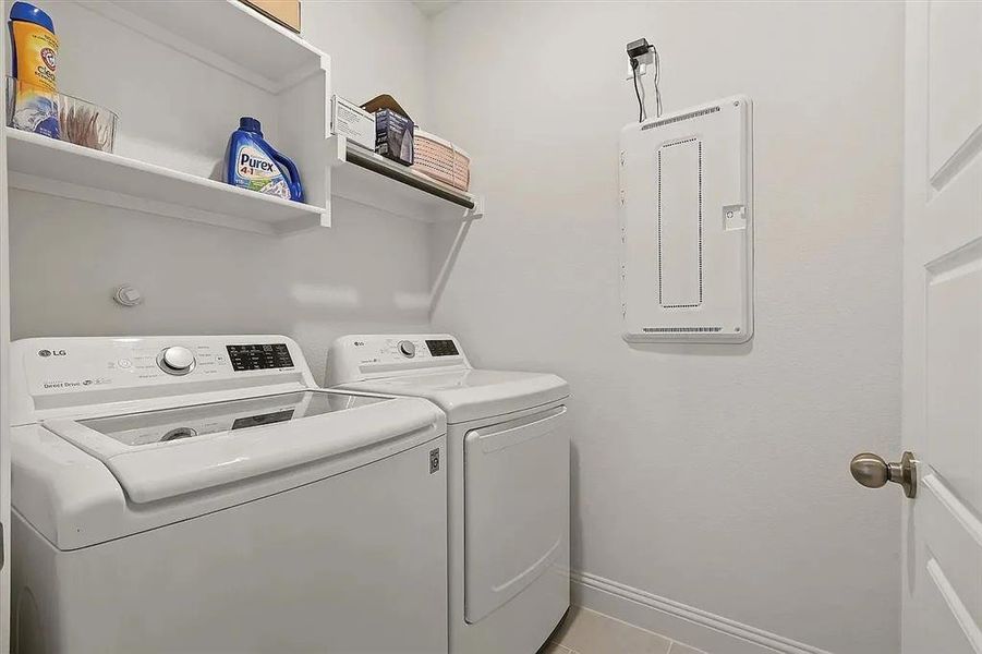 Clothes washing area with washer and clothes dryer and light tile patterned floors