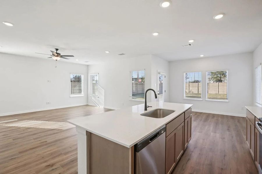 A well-lit interior boasts an open concept kitchen and living area, featuring an island with a sink. A well-lit interior boasts an open concept kitchen and living area, featuring an island with a sink.