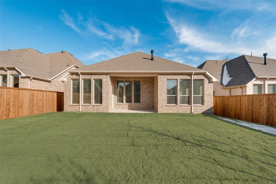 Rear view of house featuring a patio area and a lawn