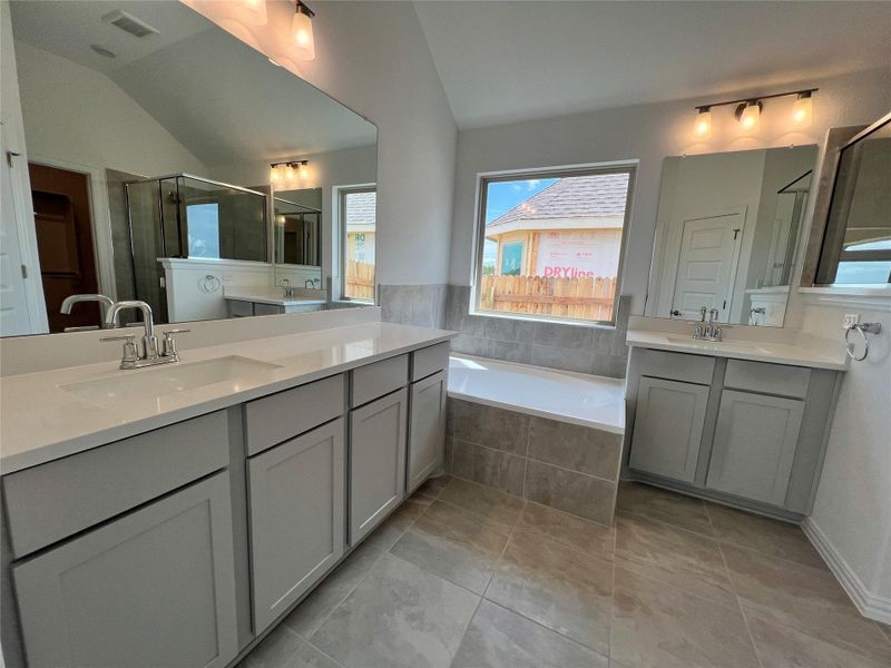 Bathroom featuring lofted ceiling, two vanities, a bath, a stall shower, and tile patterned flooring Bathroom featuring lofted ceiling, two vanities, a bath, a stall shower, and tile patterned flooring