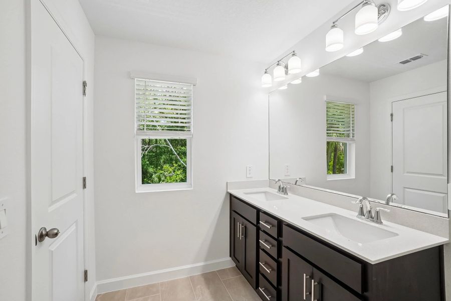 Primary bathroom features double sinks and a window for natural light