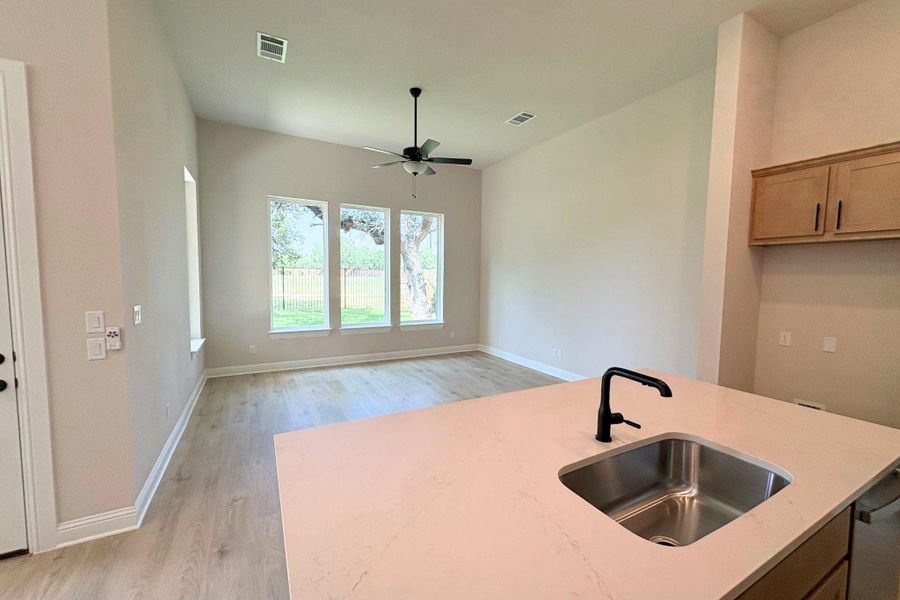 A luminous living space features generous windows, wood flooring, and an inviting kitchen island with a sink. A luminous living space features generous windows, wood flooring, and an inviting kitchen island with a sink.