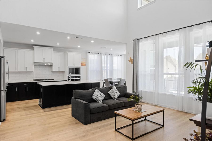 Living area featuring light wood-style floors, recessed lighting, and a high ceiling Living area featuring light wood-style floors, recessed lighting, and a high ceiling