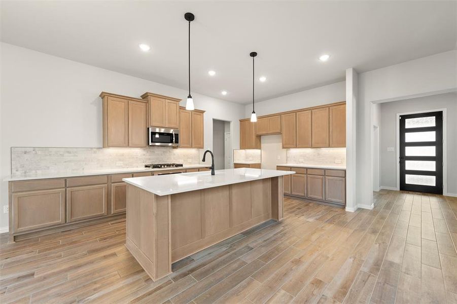 Kitchen with hanging light fixtures, a kitchen island with sink, tasteful backsplash, light wood-style floors, and recessed lighting Kitchen with hanging light fixtures, a kitchen island with sink, tasteful backsplash, light wood-style floors, and recessed lighting
