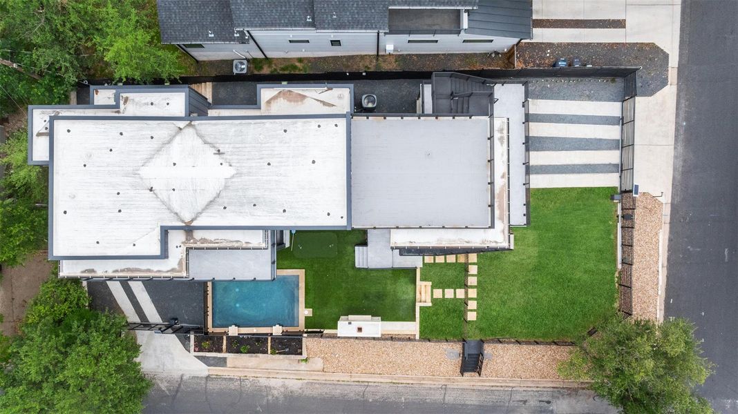 The property features a flat roof, a swimming pool, and a well-maintained lawn with stepping stones