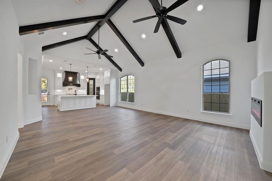 Unfurnished living room with beamed ceiling, plenty of natural light, high vaulted ceiling, dark wood-type flooring, and recessed lighting