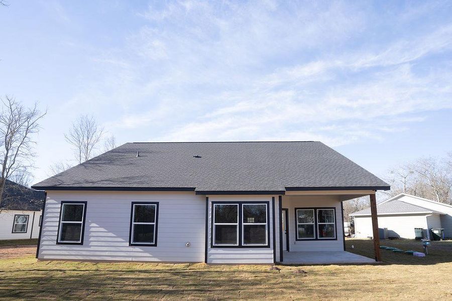 Rear view of property with a patio, a yard, and a shingled roof