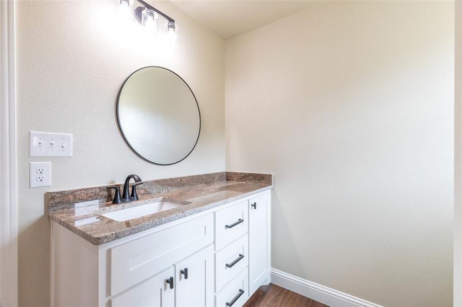 Vanity with white shaker-style cabinetry, dark bronze hardware, and an undermount sink