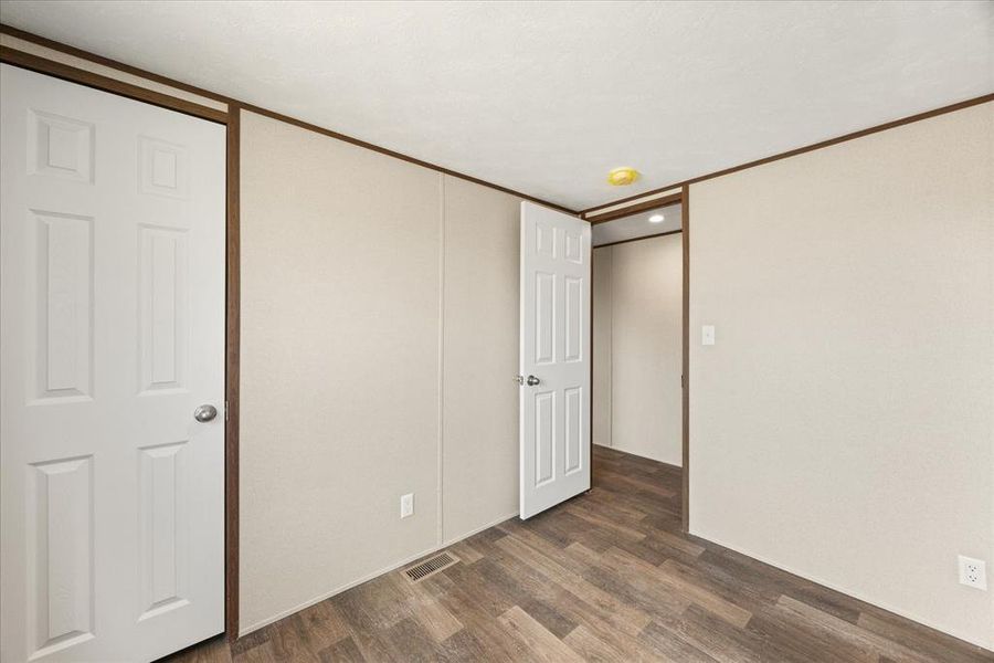 Room featuring wood-finish flooring, light-toned wall paneling, and white paneled doors