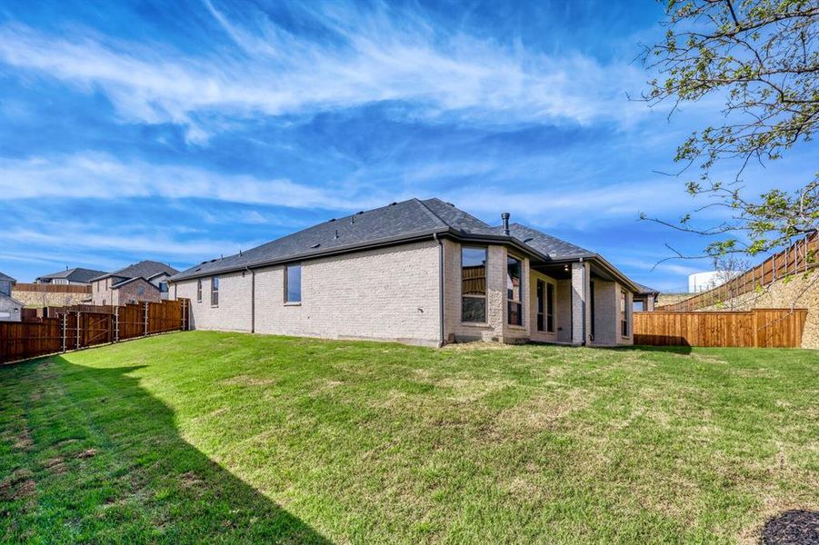 Rear view of property with brick siding, a patio area, and a fenced backyard