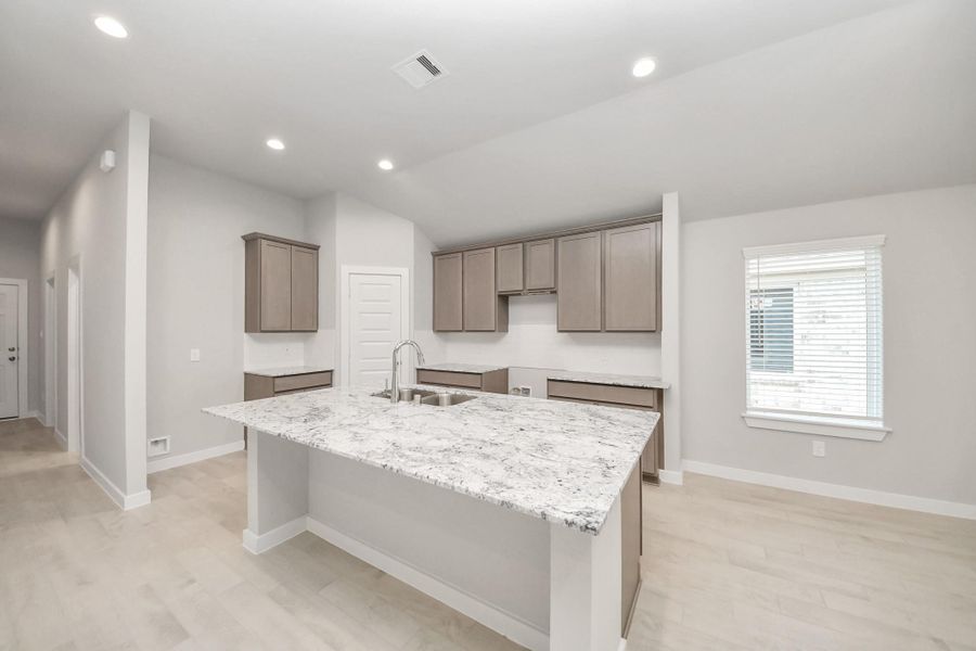 The kitchen is a culinary haven, featuring granite countertops, a tile backsplash, stainless steel appliances and 42” upper cabinets. Sample photo of completed home with similar floor plan. Actual colors and selections may vary.