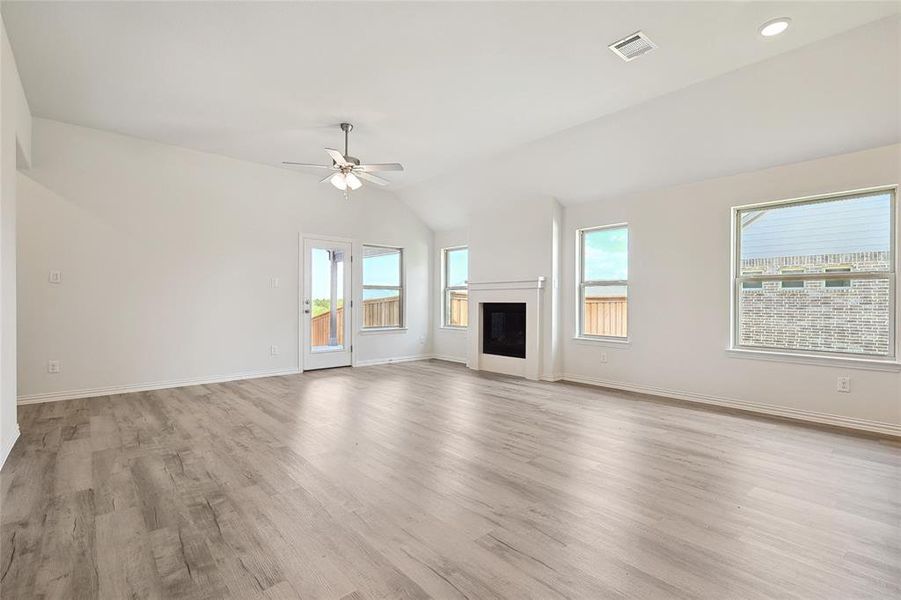 Unfurnished living room with vaulted ceiling, ceiling fan, and light hardwood / wood-style flooring