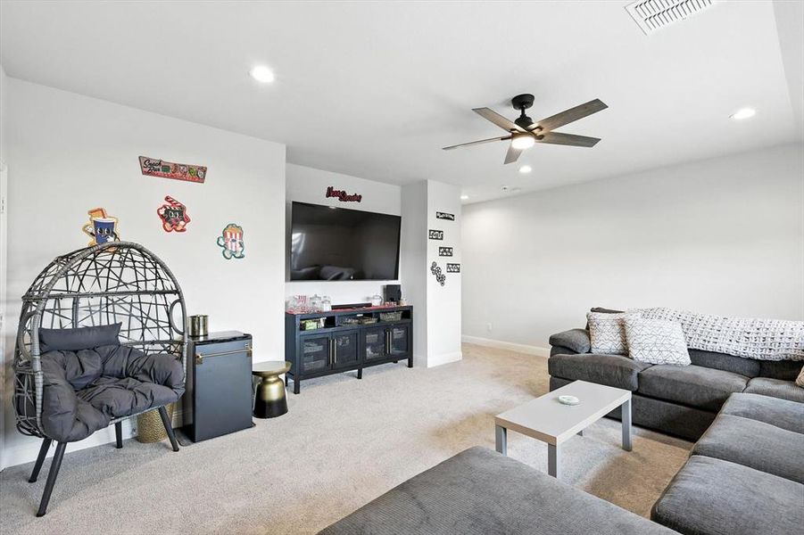 Carpeted living room with ceiling fan and recessed lighting