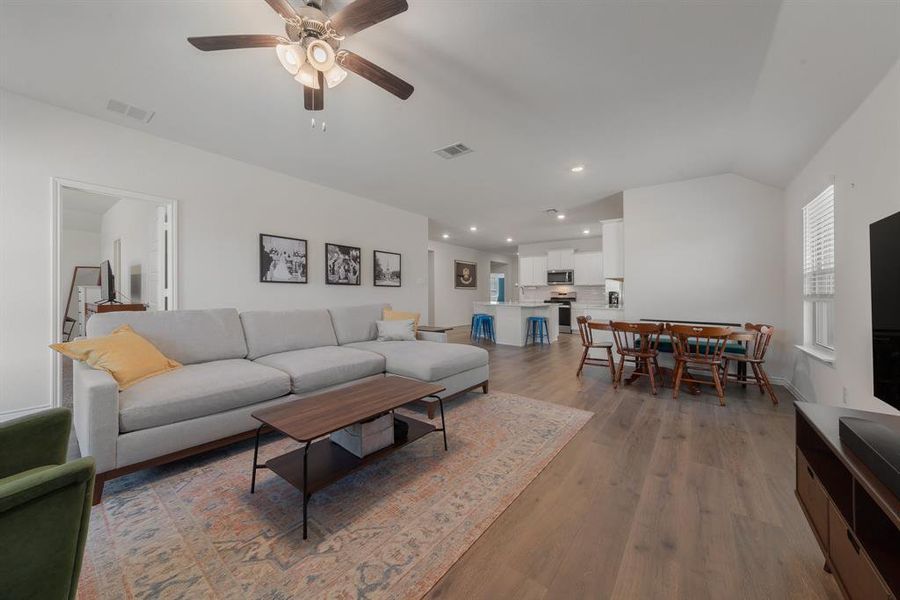 Living area featuring lofted ceiling, ceiling fan, wood finished floors, and visible vents