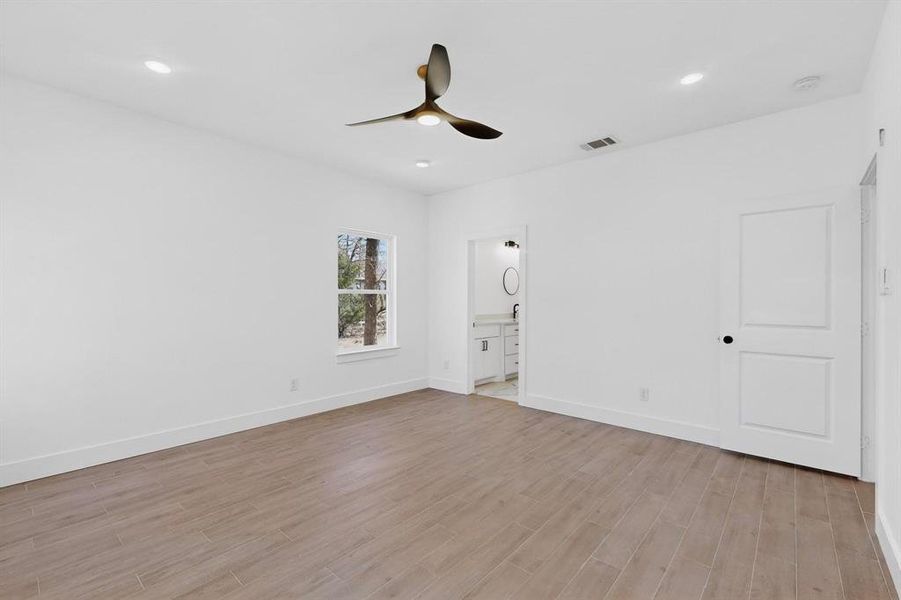 Unfurnished bedroom with light wood-type flooring, ceiling fan, ensuite bathroom, and recessed lighting