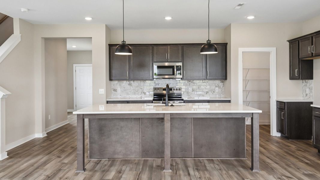 Kitchen with dark cabinetry, quartz countertops, and tile backsplash Kitchen with dark cabinetry, quartz countertops, and tile backsplash