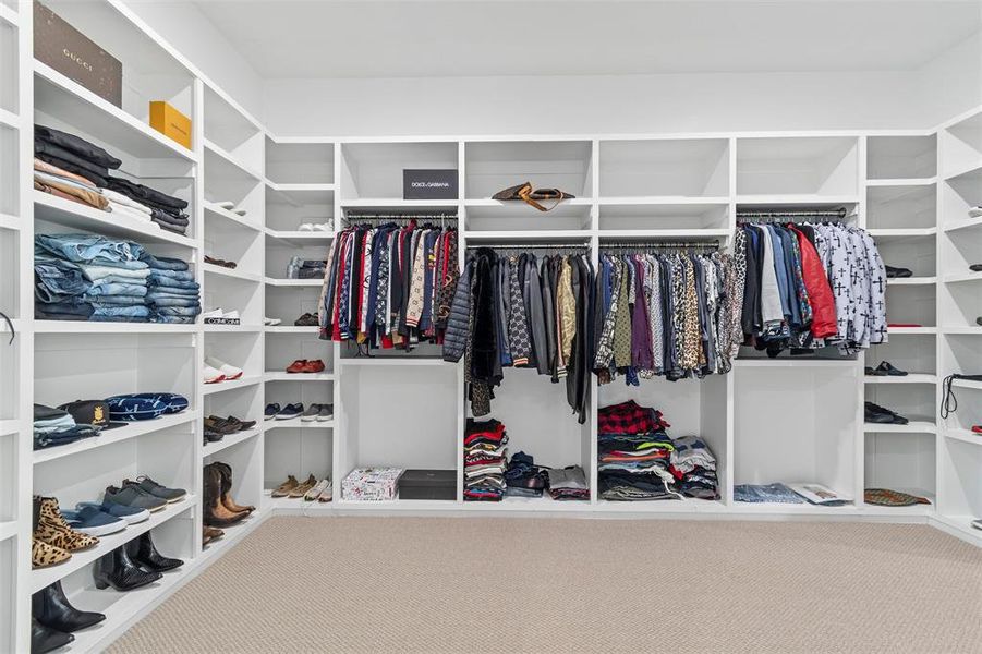 Custom closet system featuring extensive shelving, multiple hanging rods, corner storage, built-in organizers, and neutral carpeting