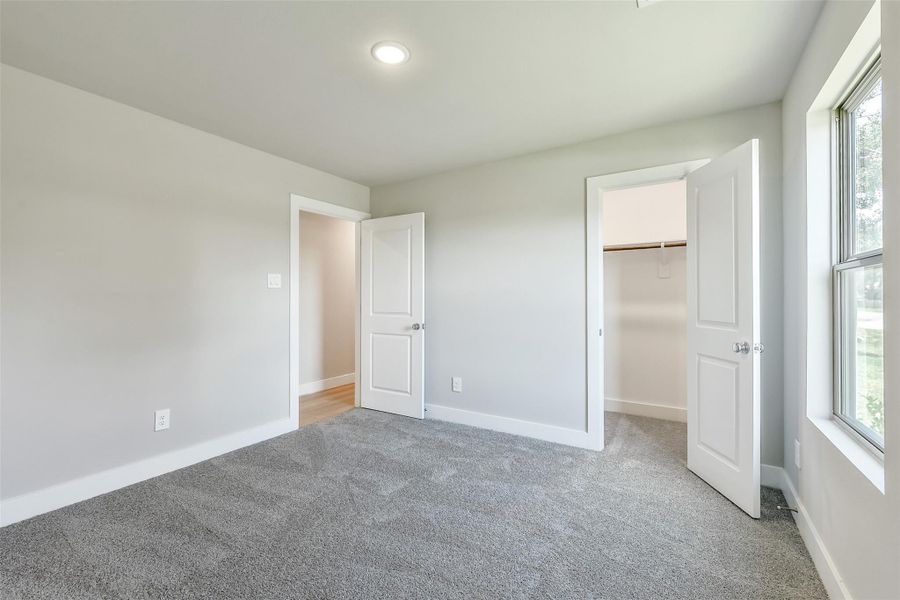 The second of two secondary bedrooms offers plush carpeting, recessed lighting, and a generously sized closet.