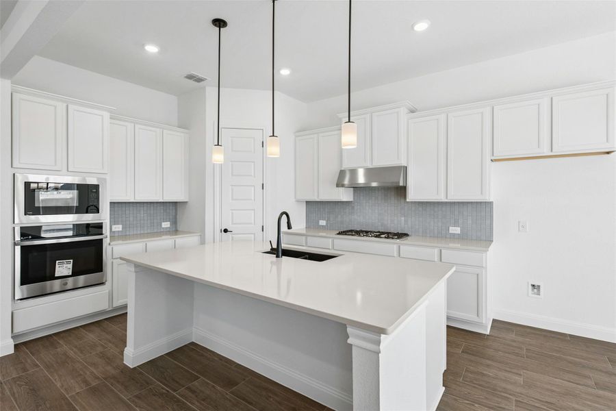 Kitchen featuring wood tiled floors, stainless steel appliances, and white cabinetry