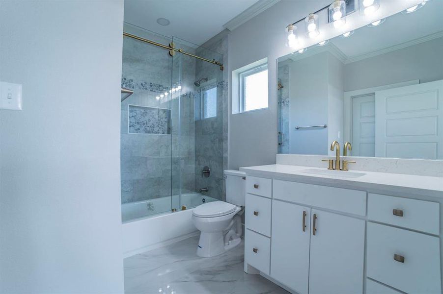 Bathroom featuring combined bath / shower with glass door, vanity, light marble finish floors, and ornamental molding