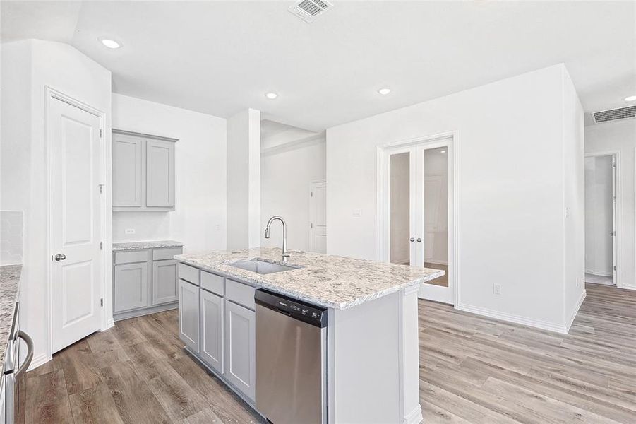 Kitchen featuring a center island with sink, light wood-type flooring, sink, and stainless steel dishwasher