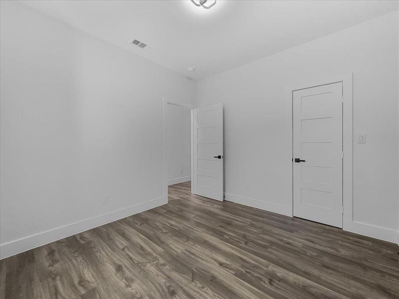 Unfurnished bedroom featuring dark wood-style floors and baseboards Unfurnished bedroom featuring dark wood-style floors and baseboards