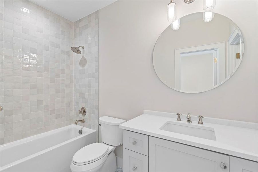 Full bathroom with toilet, tiled shower / bath combo, and vanity