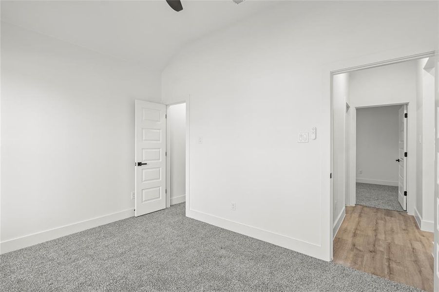 Spare room with ceiling fan, carpet, and vaulted ceiling