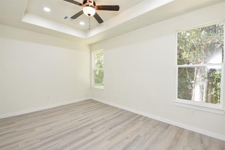 Primary Bedroom with Tray Ceiling, LED Lighting, and Ceiling Fan.