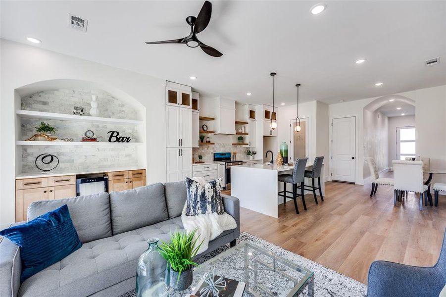 Living room with arched walkways, a ceiling fan, recessed lighting, beverage cooler, and light wood-style flooring Living room with arched walkways, a ceiling fan, recessed lighting, beverage cooler, and light wood-style flooring