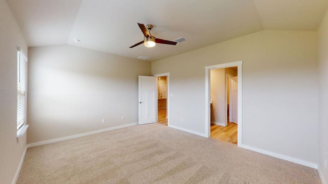 Unfurnished bedroom featuring vaulted ceiling, light carpet, and a ceiling fan