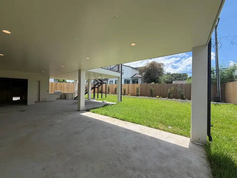 The sweeping covered backyard terrace will feature stained concrete floors, an integrated summer kitchen, recessed lighting, built-in speakers and access to the storage space under the home. The voluminous shaded footprint looks directly onto a manicured green lawn with vibrant, structured landscaping, providing a private and protected environment built for seamless grand-scale entertaining. This is a progress photo is from August 11.