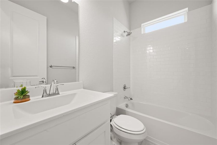 Full bathroom with vanity, tiled shower / bath combo, and toilet