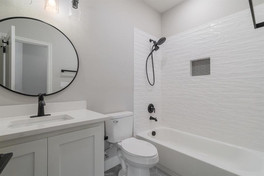 Full bathroom with tiled shower / bath, tile flooring, toilet, and vanity