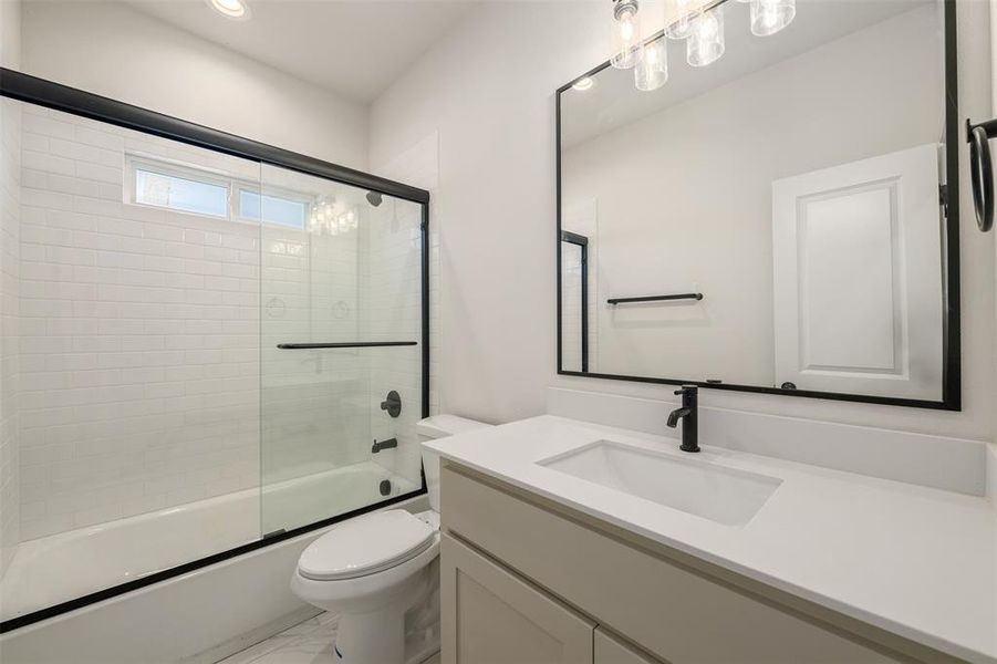 Full bathroom with vanity, bath / shower combo with glass door, and marble look tile flooring