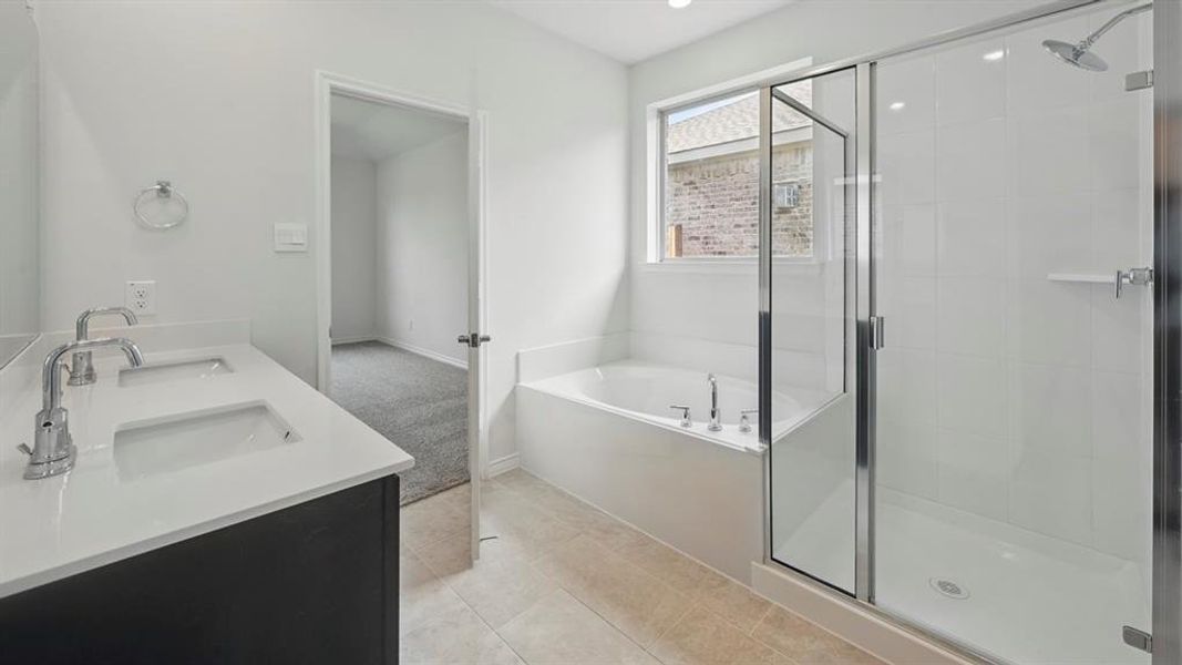 Full bathroom featuring double vanity, a bath, a stall shower, and light tile patterned floors