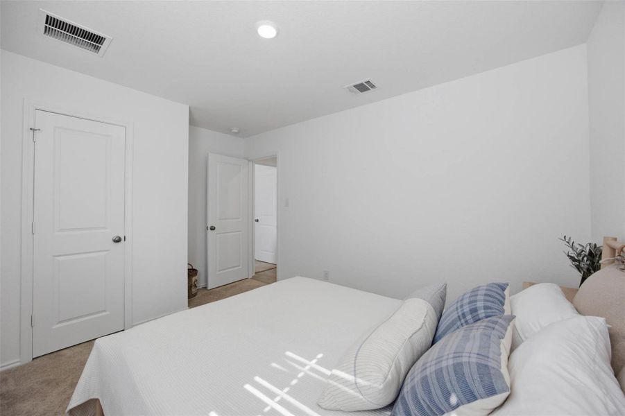 Plush carpet flooring and clean minimalist walls create a tranquil bedroom retreat.
