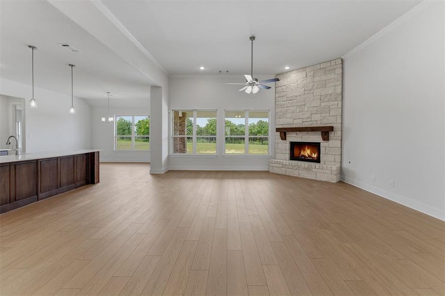Spacious interior featuring wood-finish flooring and a stone-clad fireplace with a wood mantle Spacious interior featuring wood-finish flooring and a stone-clad fireplace with a wood mantle