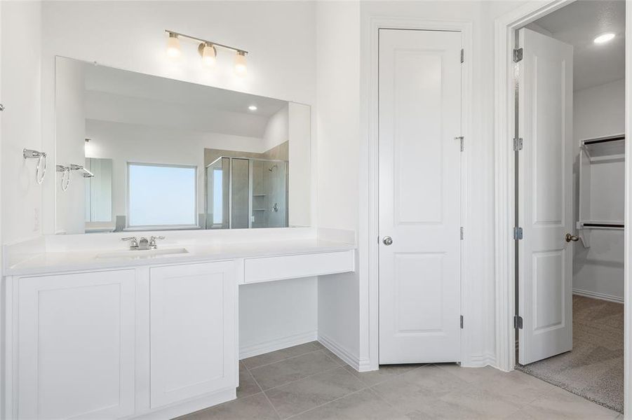 Vanity area featuring an integrated sink with a chrome faucet, extensive countertop space, and built-in white cabinetry