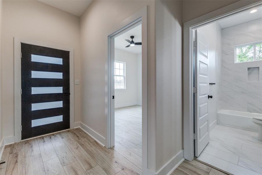 Foyer featuring a ceiling fan, a healthy amount of sunlight, and baseboards