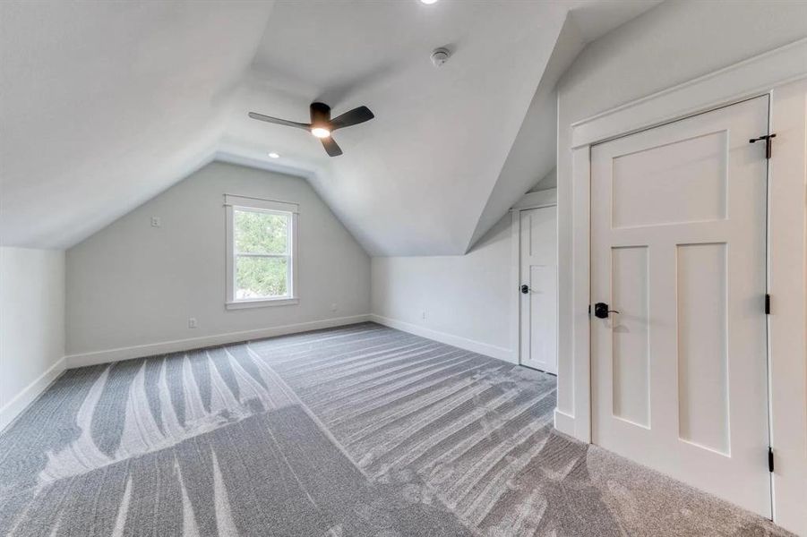 Additional living space featuring ceiling fan, vaulted ceiling, and carpet floors